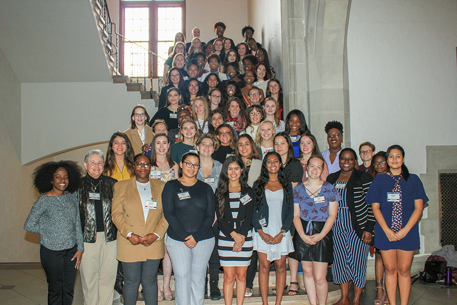 The 2018 Women's Leadership Institute, over fifty women, gathered indoors on stairs, smiling at the camera