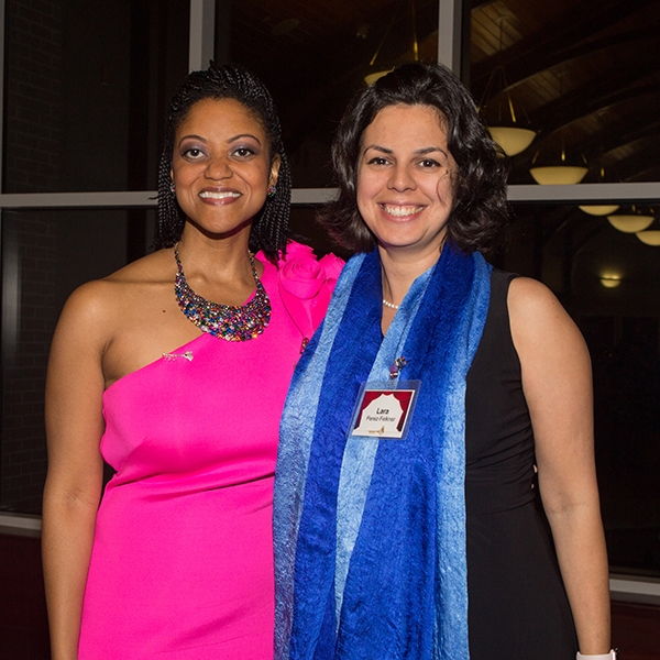 A photo of Dr. Jones wearing a blue scarf, standing with a woman wearing a pink dress, both smiling