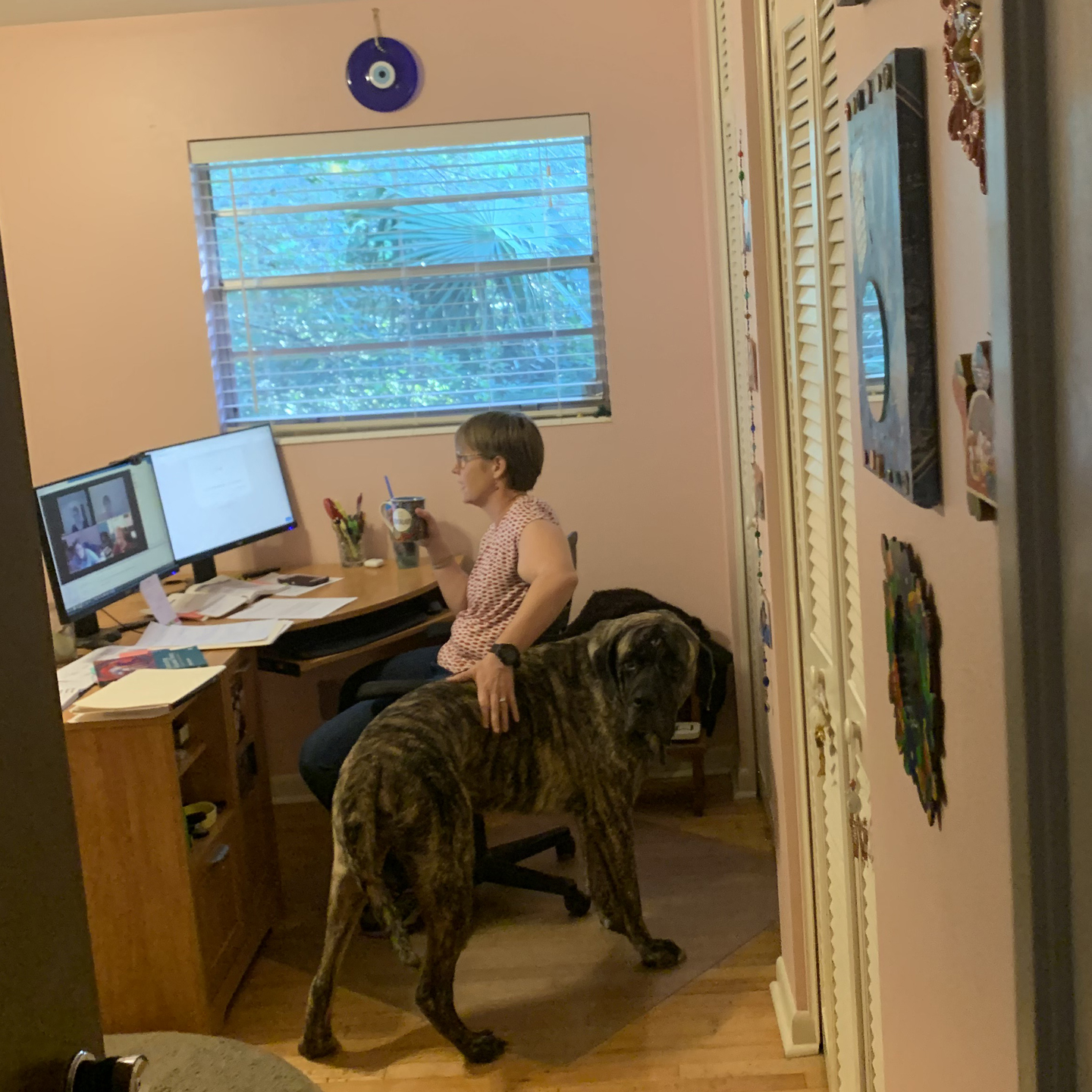 A photo of Lisa Schelbe sitting at a desk, petting a large dog