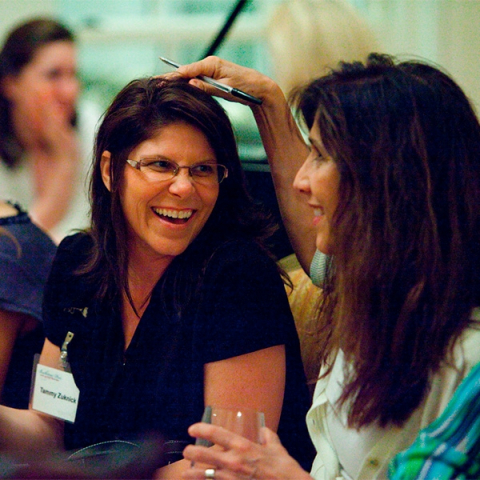 A woman in a navy blue shirt, laughing with a women in a white shirt